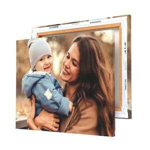 A canvas print featuring a smiling woman holding a baby dressed in a blue jacket and hat; the canvas is framed and measures 20x16 inches.