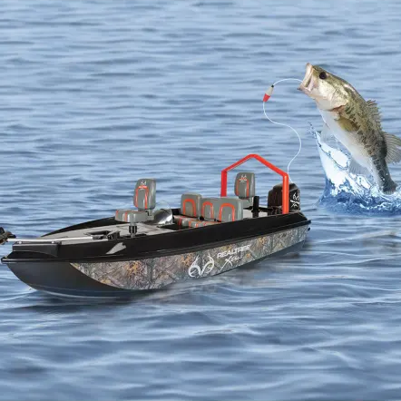 A toy fishing boat floats on the water with a fish leaping alongside.