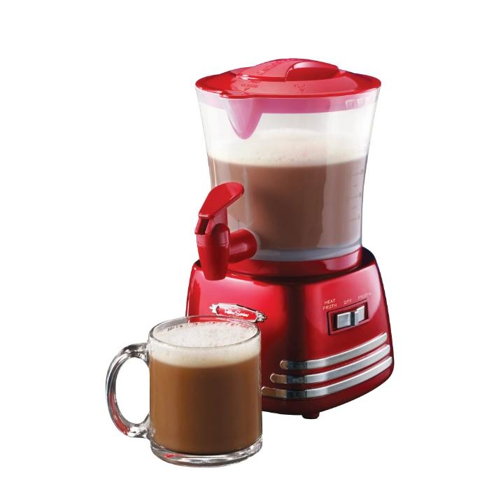 A red hot chocolate maker with a transparent top, containing a frothy beverage, is showcased alongside a mug filled with hot chocolate.