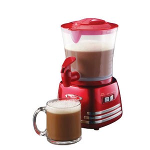 A red hot chocolate maker with a transparent top, containing a frothy beverage, is showcased alongside a mug filled with hot chocolate.