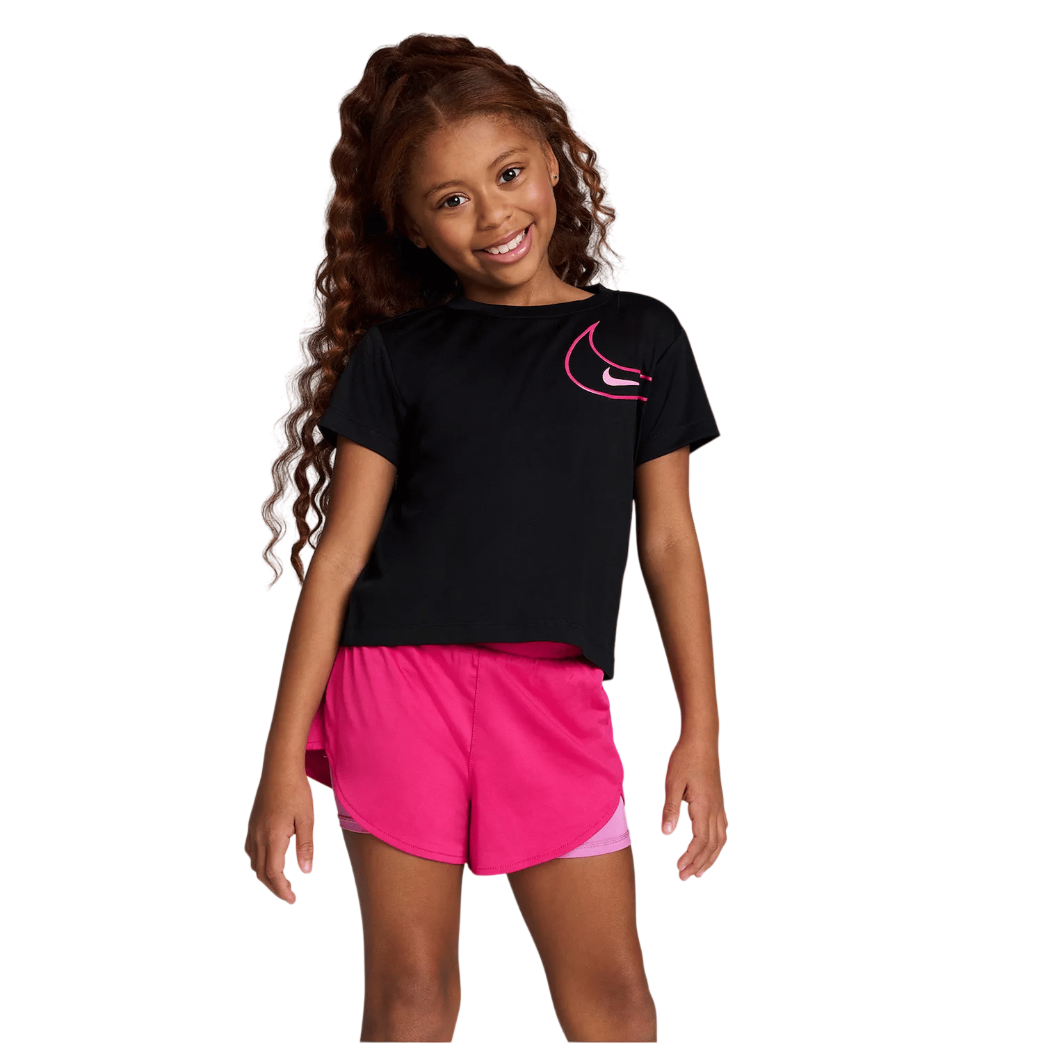 A young girl smiles wearing a black T-shirt with a pink logo and bright pink shorts.