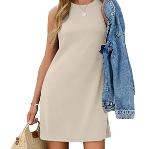 A woman wearing a sleeveless beige dress, holding a denim jacket over her shoulder and carrying a woven handbag.