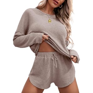A waffle-knit loungewear set in a soft beige color featuring a long-sleeve top and drawstring shorts, with a relaxed fit ideal for comfort.
