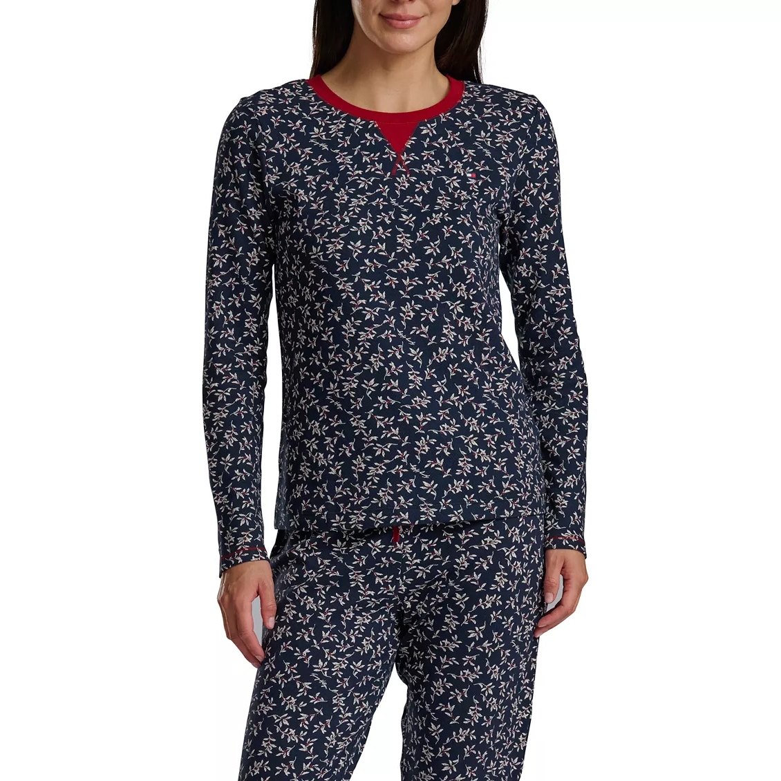 A woman is wearing a long-sleeve pajama set with a navy blue background and a small, white floral pattern. The pajamas feature a contrasting red neckline.
