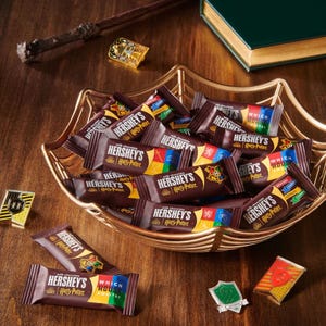 Hershey's chocolate bars with Harry Potter branding are displayed in a decorative bowl, featuring packaging designs representing various Hogwarts houses.