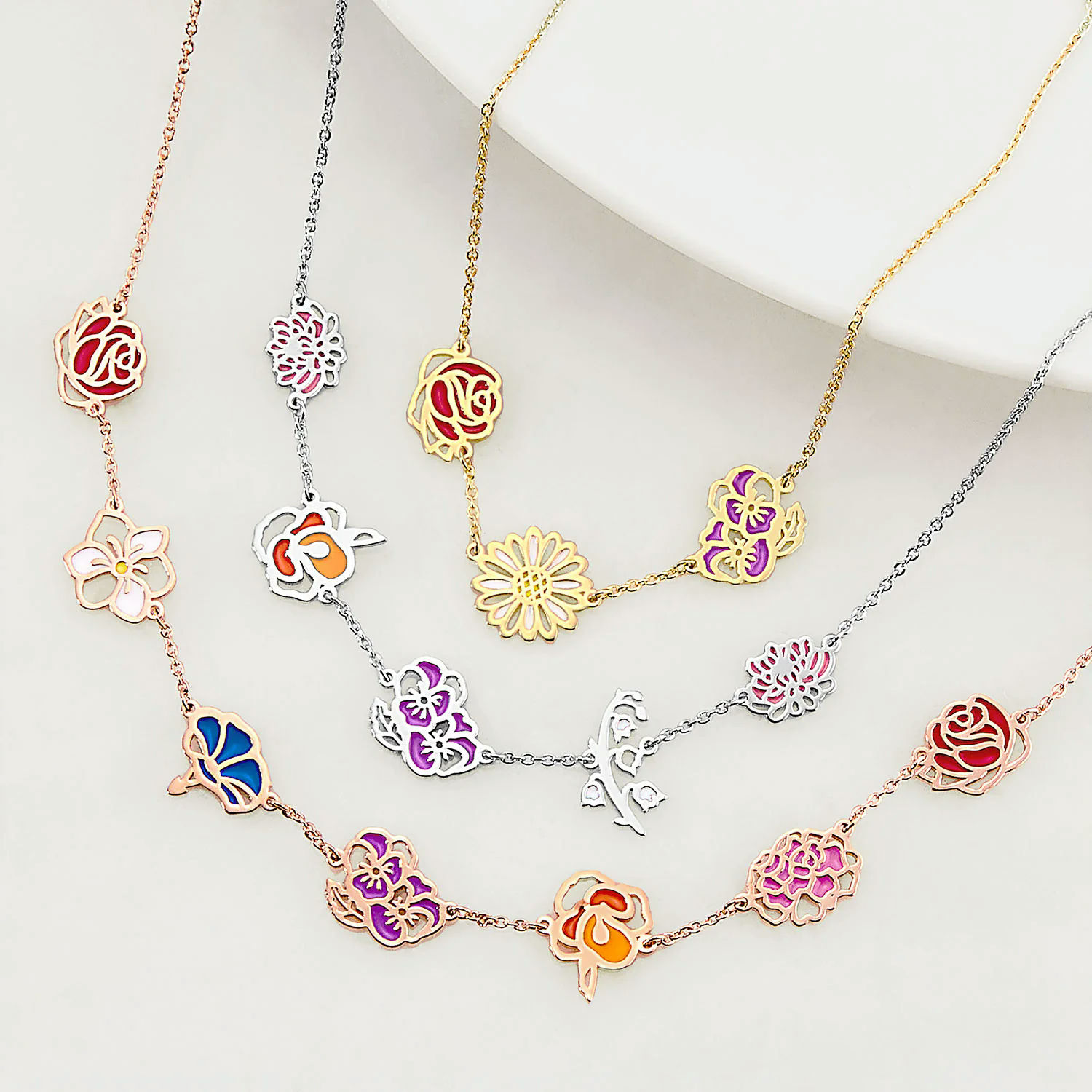 A selection of floral-themed necklaces in various colors, featuring rose, daisy, and butterfly designs on different metal finishes.