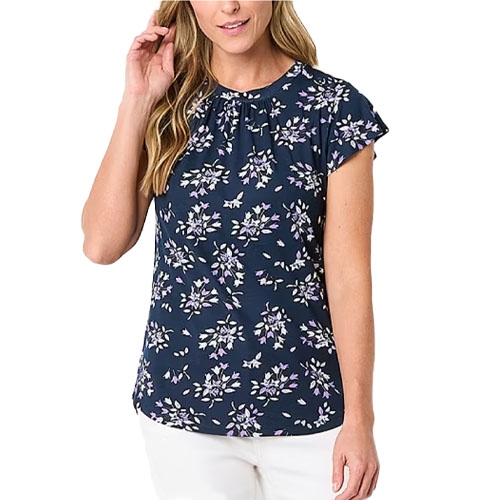 A woman is wearing a navy blue blouse with a floral pattern and short sleeves, paired with white pants.