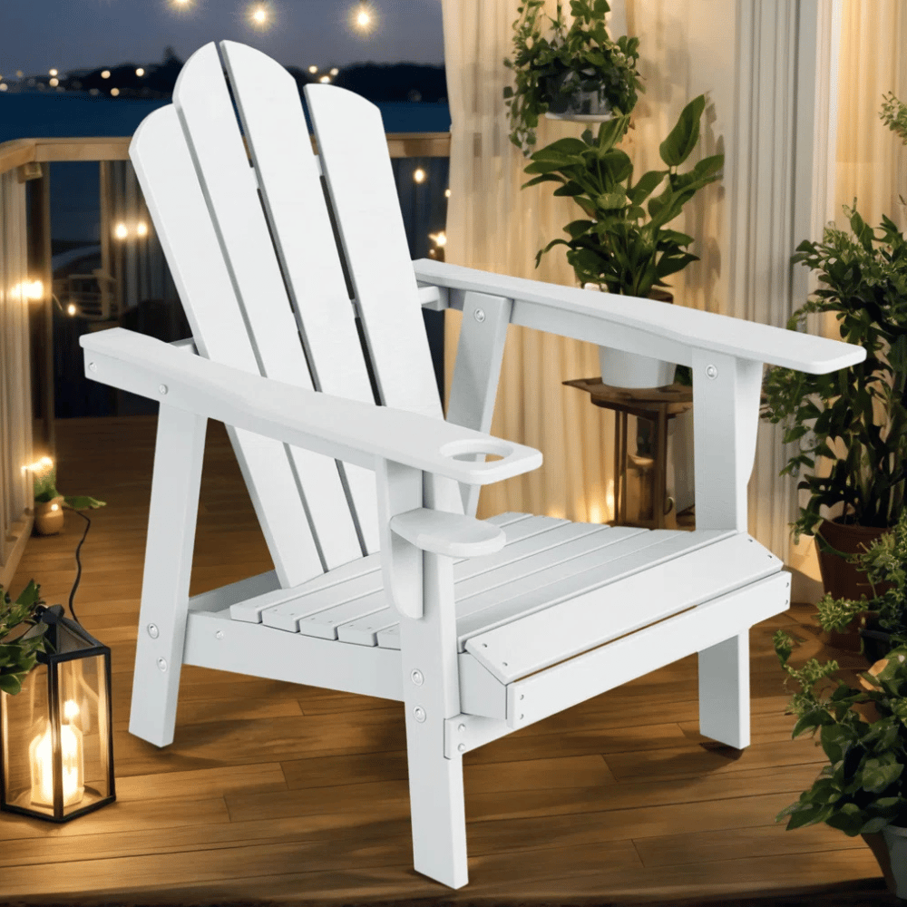 A white Adirondack chair on a wooden deck, surrounded by potted plants, with warm lights glowing in the background.