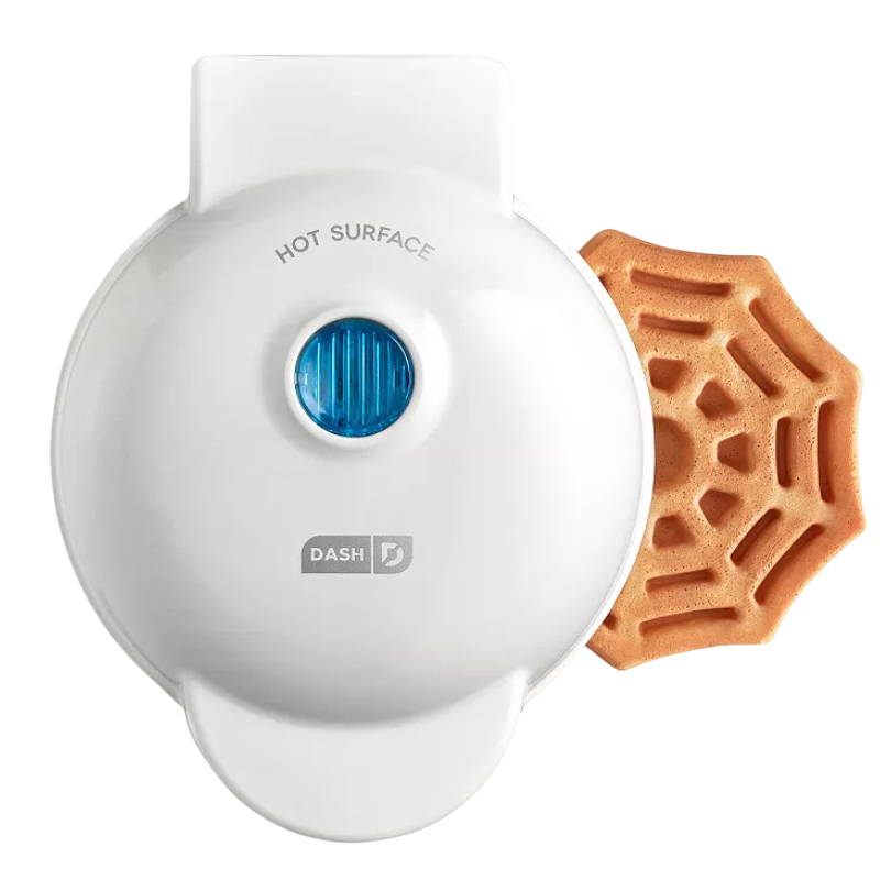 A Dash waffle maker with a spider web-shaped waffle emerging from it.