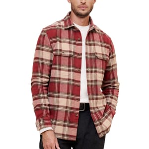 A red and beige plaid flannel shirt with button closure, featuring two chest pockets, worn over a white t-shirt with dark pants.