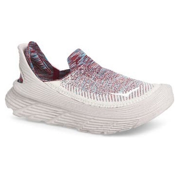 A white slip-on shoe with a textured sole featuring a multicolor knit upper in red and blue hues.