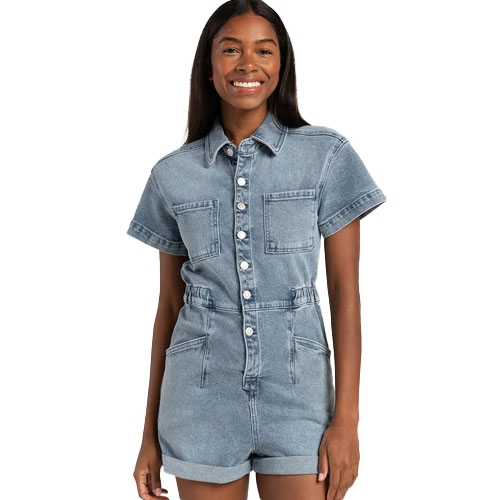 A woman is wearing a denim short-sleeve romper with two chest pockets and front button closure.