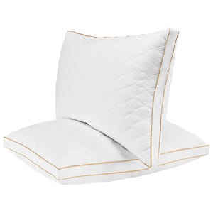 Two quilted white memory foam king pillows with gold piping detail.