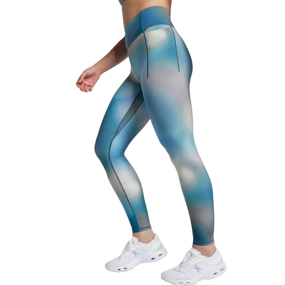 Calia Inspire High Rise Leggings feature a blue and gray gradient design with a high waistband for support. They include side pockets and are paired with white athletic shoes.