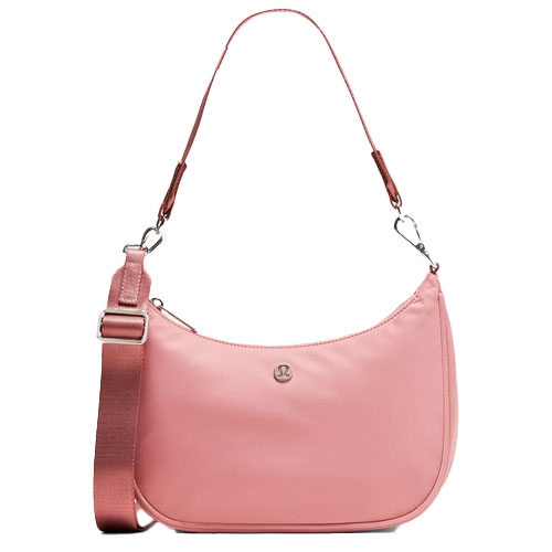 A pink lululemon shoulder bag with a rounded design, featuring an adjustable fabric strap and a silver logo on the front.