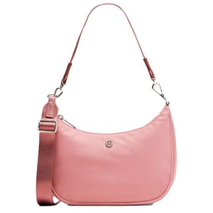 A pink lululemon shoulder bag with a rounded design, featuring an adjustable fabric strap and a silver logo on the front.