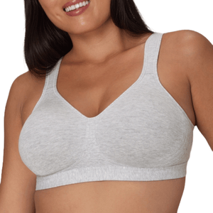 A person wearing a light gray, soft-cup bra with wide straps and a supportive band under the bust.