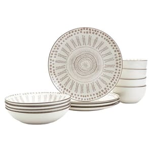 A set of beige ceramic dinnerware with intricate circular patterns, including plates and bowls, organized in a stack.