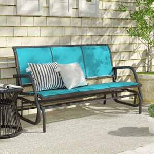 Outdoor patio setup with a turquoise glider bench featuring striped and solid cushions, a wire side table, and potted plants against a shingled wall with decorative framed art.