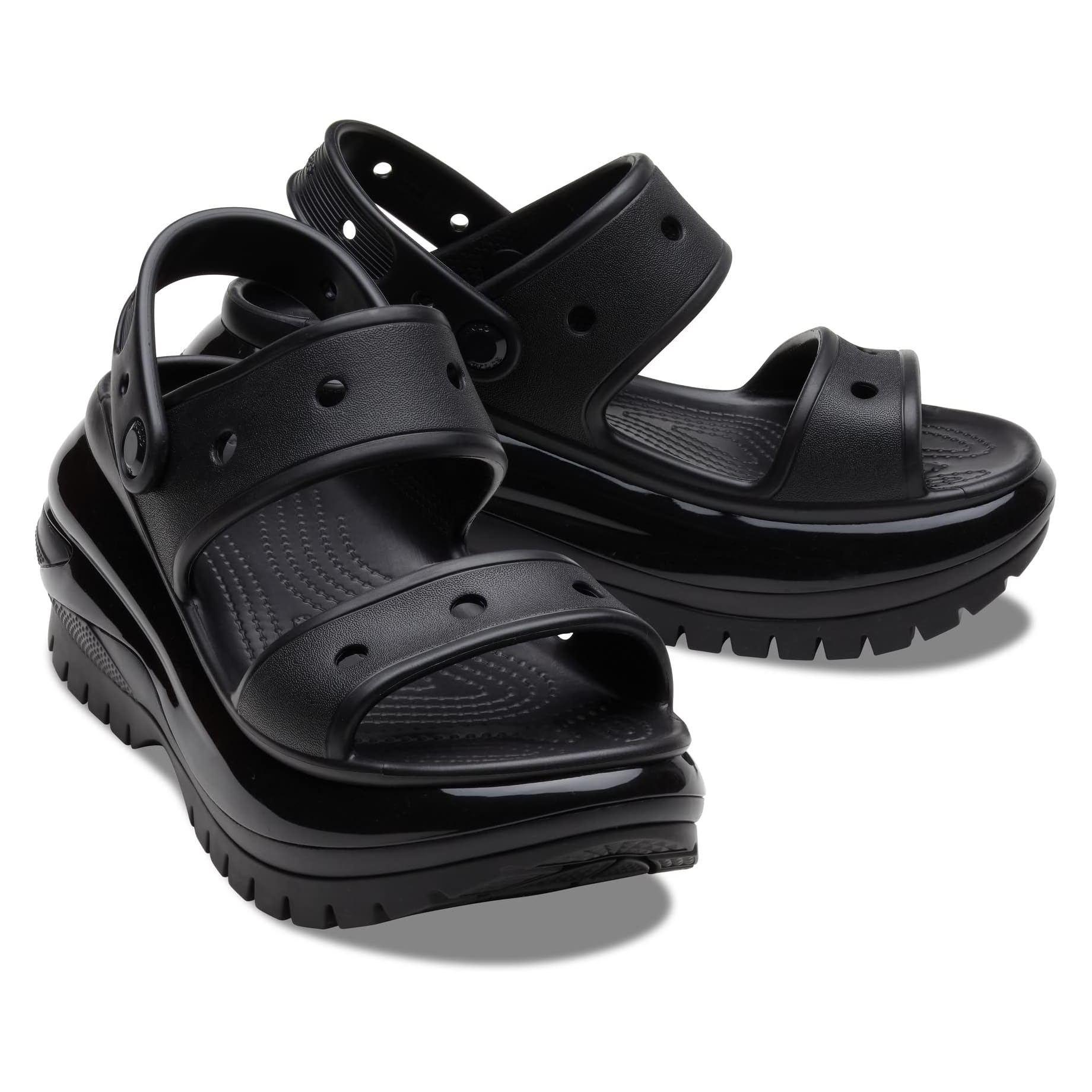 Black Crocs Mega Crush Sandals feature a chunky platform sole with multiple circular holes on the straps for ventilation. The design includes adjustable back straps and a textured footbed for comfort.