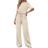 A beige two-piece outfit featuring a short-sleeve top and wide-leg pants with a drawstring waist, paired with white sneakers.