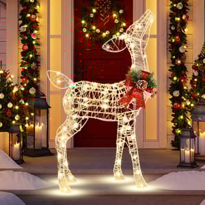 A festive lighted reindeer decoration is positioned between two snow-dusted, lantern-flanked columns adorned with garlands and a wreath on the door.