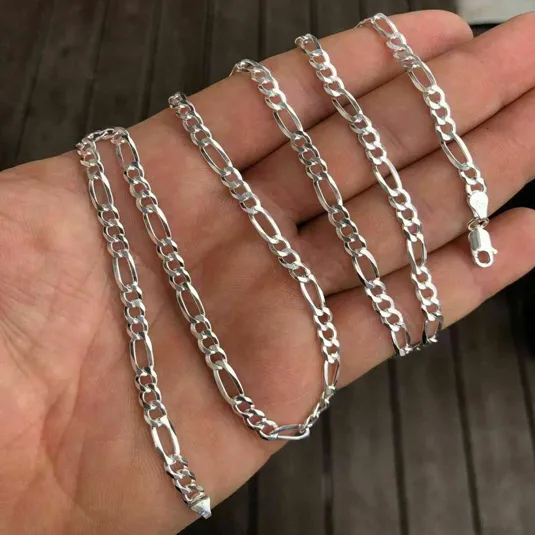 A silver Figaro chain is shown, featuring a pattern of three small circular links followed by one elongated oval link, with a lobster clasp for fastening.