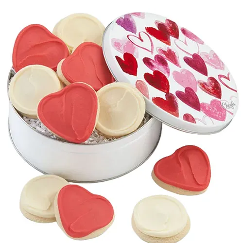 A round tin with a heart design on the lid contains frosted heart-shaped and round sugar cookies in red and white.
