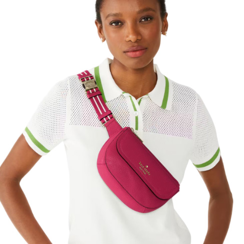 A woman is wearing a white polo shirt with green trim and a pink waist bag with a striped strap.