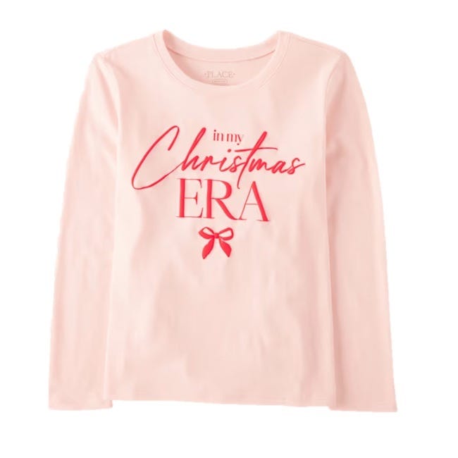 Light pink long-sleeve shirt featuring the text \“in my Christmas ERA\“ in red, with a small red bow design below.