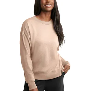 A person is wearing a beige, long-sleeved sweatshirt paired with black pants.