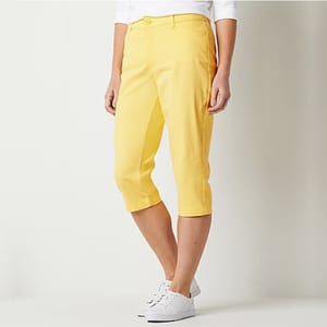 A pair of yellow capri pants and white sneakers worn by a model.