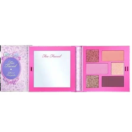An open Too Faced makeup palette with six eyeshadow shades in pink and purple tones, next to an integrated mirror, featuring a delicate design on the lid.