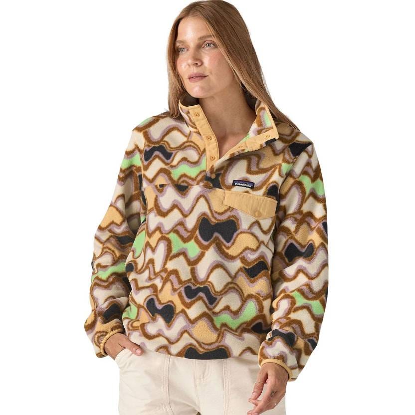 A woman is wearing a patterned Patagonia fleece pullover with a wavy, multicolored design, featuring a button-up collar and a chest pocket.
