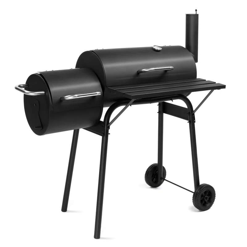 A black 36\“ charcoal grill and smoker featuring a horizontal barrel design with side firebox, a chimney, metal handles, two wheels, and a flat shelf for prep. Sturdy metal legs provide stability.