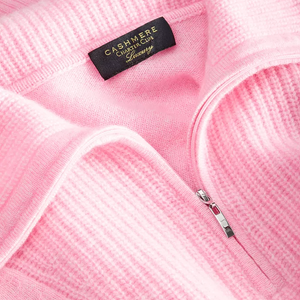 A pink cashmere sweater with a zipper and a \“Cashmere Charter Club Luxury\“ label displayed. The fabric is ribbed, highlighting its texture.