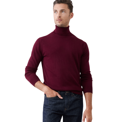 A man is wearing a burgundy turtleneck sweater paired with dark blue jeans against a neutral background.