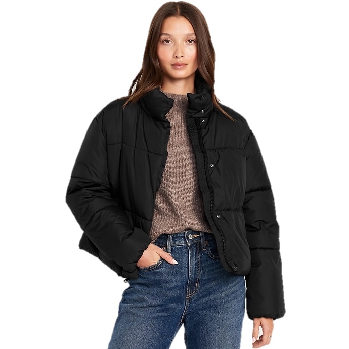 A woman is wearing a black Old Navy Quilted Puffer Jacket, featuring a high collar and button closure. She pairs it with a brown sweater and high-waisted blue jeans, creating a casual and cozy look.