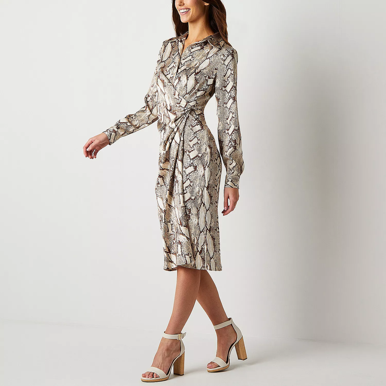 A woman wearing a snake print wrap dress paired with beige strappy heels.