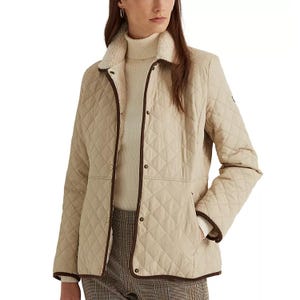 A quilted coat with a faux-sherpa collar, featuring a zip and snap-button front closure, and tailored with a straight fit. The coat is beige with contrasting brown trim.