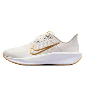 A white athletic shoe features a gold swoosh logo, breathable mesh upper, and cushioned sole for comfort.