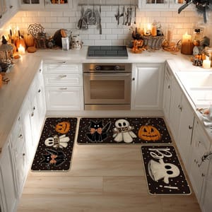 Halloween-themed kitchen rugs with ghost, cat, pumpkin designs and \“Boo\“ text decorate a white kitchen with candles and festive items.
