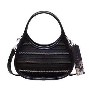 A black handbag with a unique silhouette features horizontal zipper detailing and comes with a detachable strap and a decorative tag.