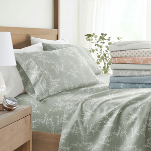 Patterned bedding comforter, pillowcases, and a stack of folded coordinating sheets displayed on a bed.