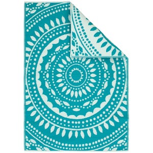 A turquoise and white patterned beach towel with mandala design.