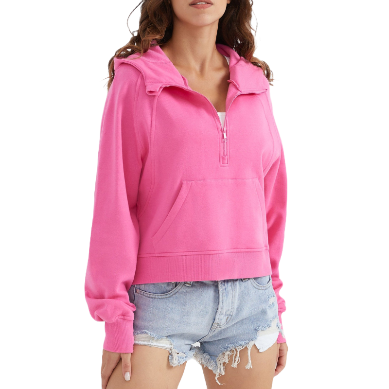 A pink half-zip cropped sweatshirt with a kangaroo pocket and ribbed cuffs, paired with light blue distressed denim shorts.