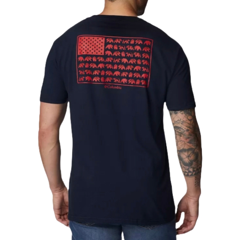 A man wearing a navy T-shirt with a red graphic resembling the American flag, featuring bear silhouettes in place of stripes. The shirt is branded \“Columbia\“ and he has tattoos on his arm.