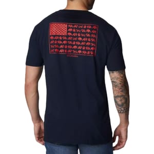 A man wearing a navy T-shirt with a red graphic resembling the American flag, featuring bear silhouettes in place of stripes. The shirt is branded \“Columbia\“ and he has tattoos on his arm.