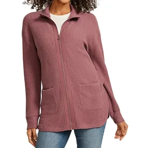 A mauve zip-up cardigan with a waffle-knit texture, featuring a full front zipper and two front pockets, paired with blue jeans.