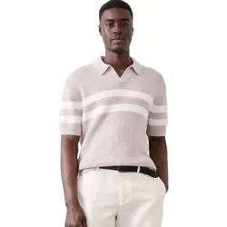 A man is wearing a light-colored, short-sleeve knit polo with white horizontal stripes, paired with light beige shorts and a black belt.